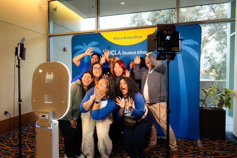 A group of people taking a selfie in front of a UCLA Student Affairs backdrop.