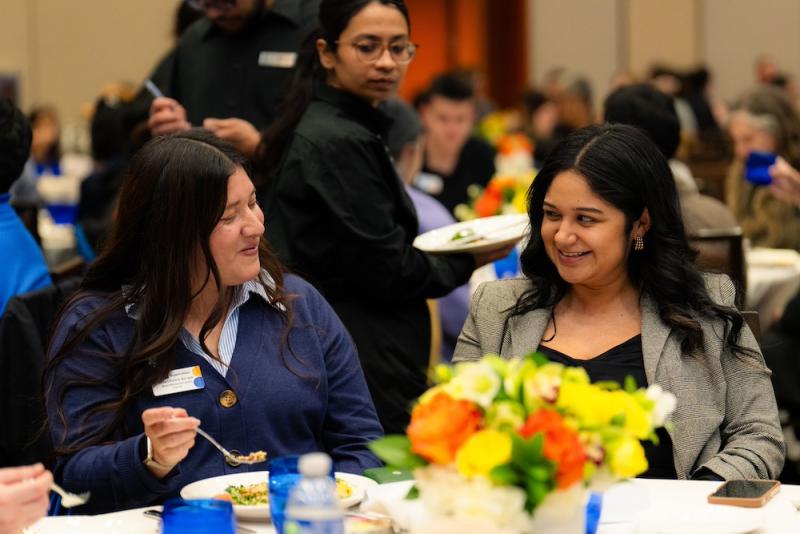 2 women eating dinner together at an event.