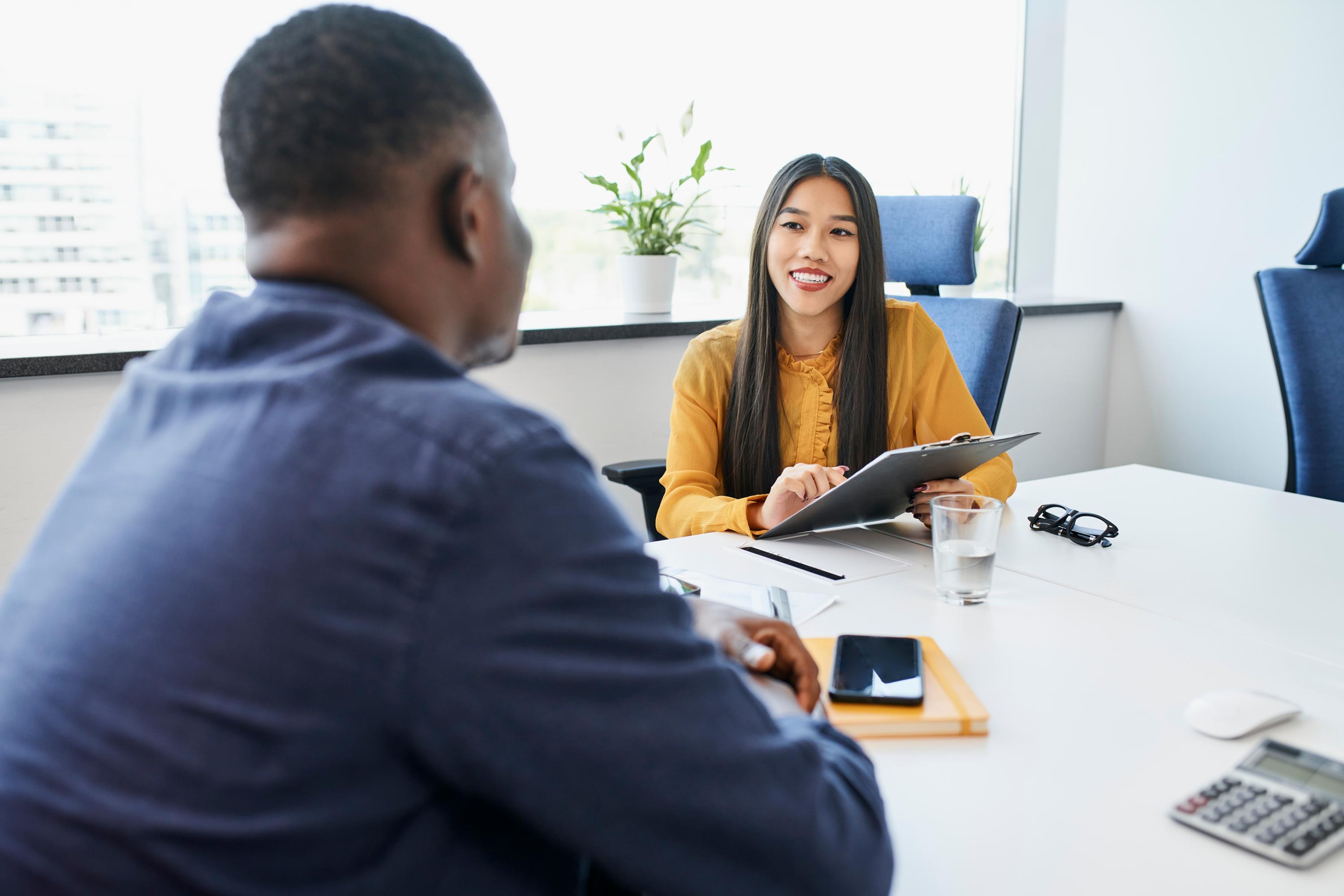 Two staff members having a conversation while sitting at a table