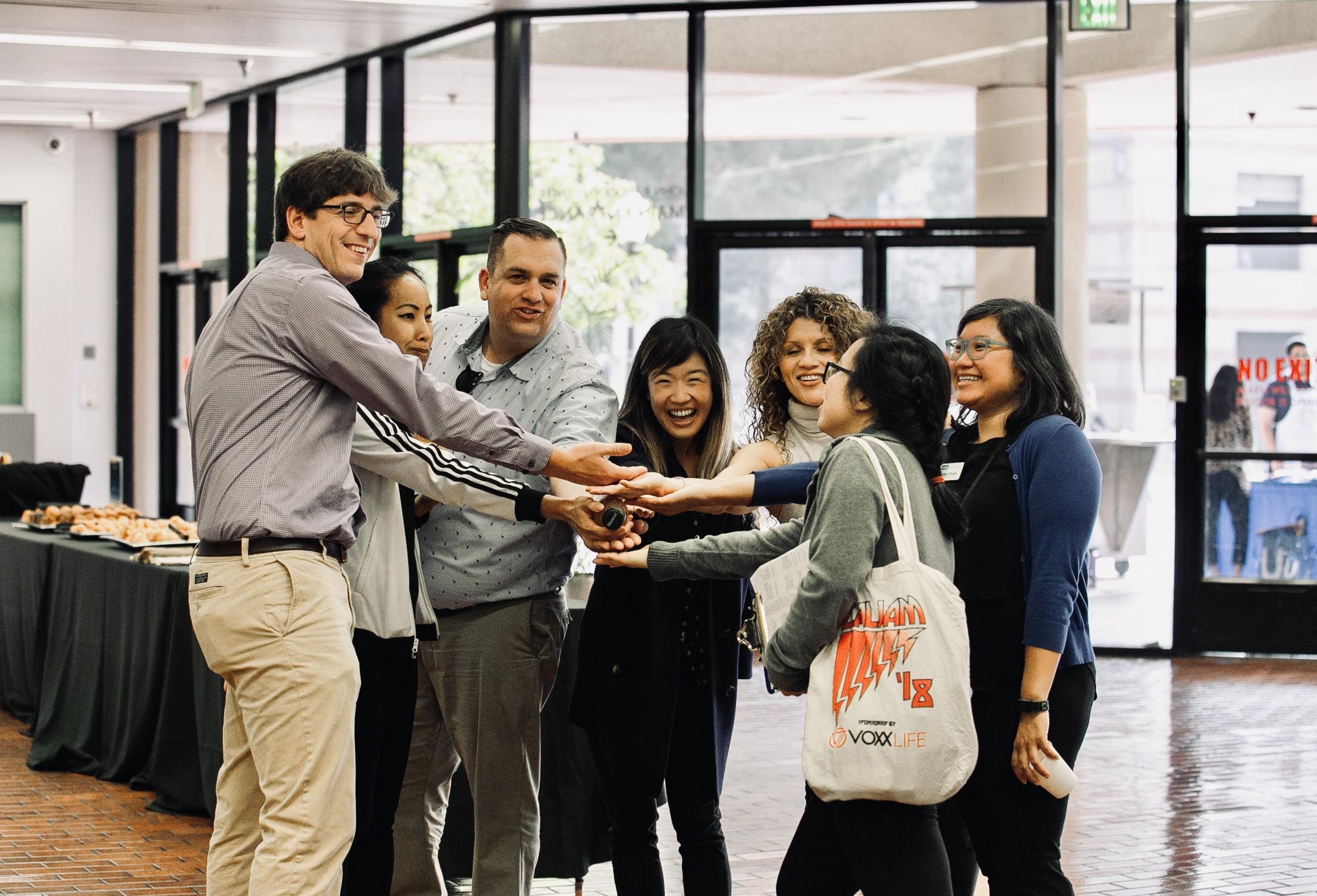 Seven colleagues doing a team hand stack.