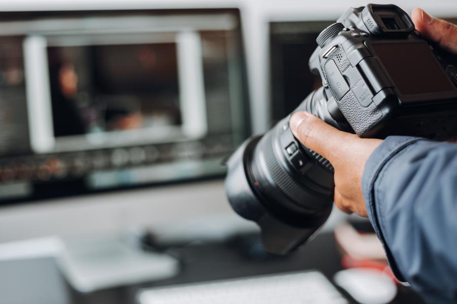 Person holding camera in front of a laptop